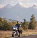 Bearded biker in black leather jacket on modern motorcycle on country roadside. Royalty Free Stock Photo