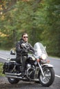 Bearded biker in black leather jacket on modern motorcycle on country roadside. Royalty Free Stock Photo