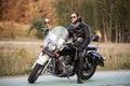 Bearded biker in black leather jacket on modern motorcycle on country roadside. Royalty Free Stock Photo