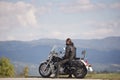 Bearded biker with long hair in black leather jacket and sunglasses sitting on modern motorcycle. Royalty Free Stock Photo