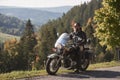 Bearded biker with long hair in black leather jacket and sunglasses sitting on modern motorcycle. Royalty Free Stock Photo