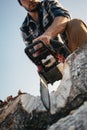 Bearded brutal lumberjack wearing plaid shirt sawing tree with chainsaw for work on sawmill. Wooden sawdust fly apart Royalty Free Stock Photo