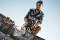 Bearded brutal lumberjack worker saw the tree with a chainsaw