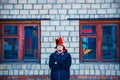 Bearded brutal man in the hat of a buffoon stands near the brick wall