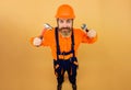 Bearded builder in safety helmet and overalls with hammer and adjustable spanner. Construction worker in hardhat with Royalty Free Stock Photo