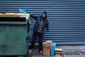 Bearded bum searching food in trashcan on street