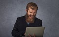 Bearded business man holding computer screaming isolated grey gray background Royalty Free Stock Photo