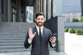Bearded businessman in a formal suit, talking on video call using smartphone on urban city street confident business man, Royalty Free Stock Photo