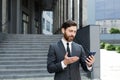 Bearded businessman in a formal suit, talking on video call using smartphone on urban city street confident business man, Royalty Free Stock Photo