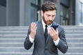 Bearded businessman in a formal suit, talking on video call using smartphone on urban city street confident business man, Royalty Free Stock Photo