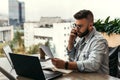 Bearded businessman hipster talking on phone while sitting at desk in office, sad looking at documents. Fall in profits. Royalty Free Stock Photo
