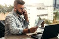 Bearded businessman hipster talking on phone while sitting at desk in office, sad looking at documents. Fall in profits. Royalty Free Stock Photo