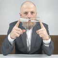 Bearded businessman holds an hourglass near the face. concept of time value for business