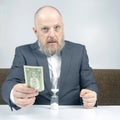 Bearded businessman offers payment for work with money against the background of the hourglass. concept of value of time to pay