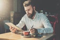 Bearded businessman sits in cafe at table,uses tablet computer and writes in notebook.Man is working Royalty Free Stock Photo