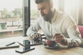 Bearded businessman sits in office at table,uses tablet computer.On desk is notebook,smartphone.Man working,studying Royalty Free Stock Photo