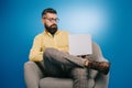 Bearded businessman sitting in armchair with laptop, isolated Royalty Free Stock Photo