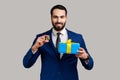 Bearded businessman standing holding present box and golden bitcoin, crypto currency as a gift. Royalty Free Stock Photo