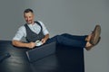 Bearded businessman with stylish mustache, dressed in classic suit has put his legs on table, holding cup of coffee Royalty Free Stock Photo