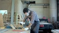 Bearded carpenter in safety glasses working with electric planer in workshop