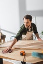 Bearded carpenter taking sandpaper while working