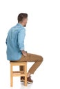 Bearded casual guy sitting on chair and holding hands in pockets