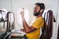 Bearded caucasian adult man sit down inside the airplane flight asking for hostess help -modern internet connection onboard