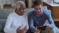 Bearded Caucasian guy helping senior Black man with using tablet