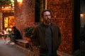 Bearded Caucasian man with brown jacket posing in front of a brick wall Royalty Free Stock Photo