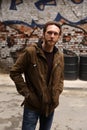 Bearded Caucasian man with a brown jacket posing in front of a graffiti Royalty Free Stock Photo