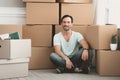 Bearded Caucasian Sits near Large Cardboard Boxes.