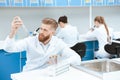 Bearded chemist in white coat examining test tube in laboratory