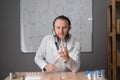 a bearded chemistry teacher with a headset in white sits on a chair against the background of a marker board with Royalty Free Stock Photo