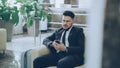 Bearded concentrated businessman using smartphone sit on armchair inside luxury hotel after arrivel to business meeting Royalty Free Stock Photo