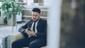 Bearded concentrated businessman using smartphone sit on armchair inside luxury hotel after arrivel to business meeting Royalty Free Stock Photo