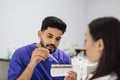 Bearded confident male dentist checking and selecting color of young woman teeth