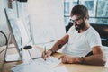 Bearded coworker professional wearing eye glasses working at modern loft studio-office with desktop computer.White blank