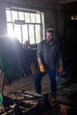 bearded craftsman in protective gloves standing near machine