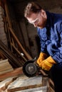 bearded craftsman in protective googles and gloves using grinding machine