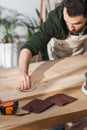 Bearded craftsman sanding wooden board near