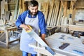 Bearded Craftsman Sawing Wooden Board