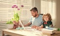 bearded dad writing school homework with his child son in classroom, childhood