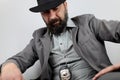 Bearded detective with hat and police badge kneel looks down at the crime scene. Royalty Free Stock Photo