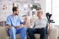 Bearded doctor in nursing home giving pills