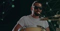 Bearded drummer playing drum kit with sunglasses in studio with glowing green node line graphics Royalty Free Stock Photo