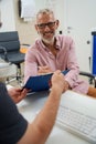 Bearded elderly man signing documents in doctors office