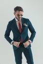 Bearded elegant guy looking down and buttoning suit