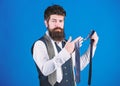 Bearded but elegant. Long bearded hipster choosing neckwear. Bearded man holding necktie. Cheerful man with unshaven