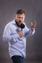 Bearded emotional singer with microphone dressed in shirt studio portrait.