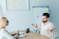 Bearded employee showing shrug gesture near attractive recruiter